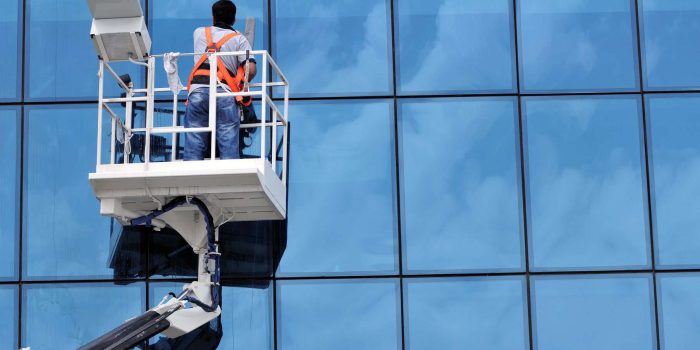 Window washing on high-rise office building in crane beam