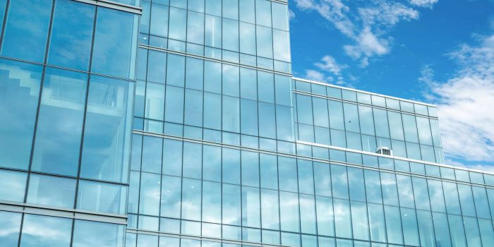 Modern sustainable glass office building. Exterior view of corporate headquarters glass building architecture. Energy-efficient building. Financial business center tower. Glass windows of company.